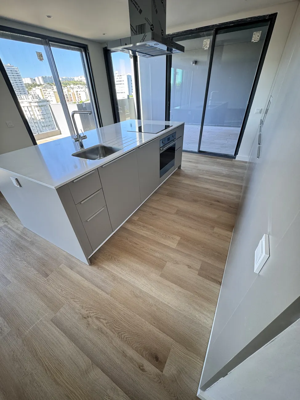 Cozinha aberta com ilha central e pavimento vinílico SPC click em carvalho instalado pela Revest